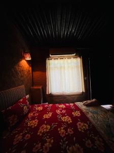 une chambre avec une couette rouge et une fenêtre dans l'établissement The Mudcasa, à Udaipur