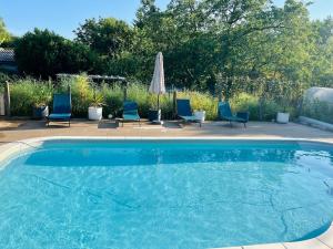 ein Swimmingpool mit Stühlen und einem Sonnenschirm in der Unterkunft Domaine Magnolia in Les Abrets en Dauphine