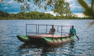 two men are rowing a boat on a lake at Riverview Bentota in Bentota