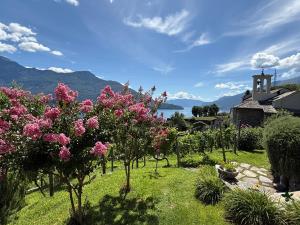 a garden with trees and flowers and a church at Casa Nonna Nina in Vercana