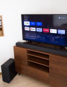 a flat screen tv sitting on top of a wooden entertainment center at 大戸別邸 Oto Villa 小江戸佐原や鹿島香取神宮観光にも便利な一棟貸しの宿 in Katori