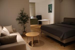 a bedroom with a bed and a couch and a table at GIA Hotel & Serviced Apartment in Nhơn Trạch