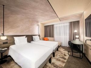 a hotel room with two beds and a desk at Novotel Warszawa Centrum in Warsaw +170 photos