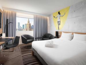 a hotel room with a bed and a painting of a woman on the wall at Novotel Warszawa Centrum in Warsaw