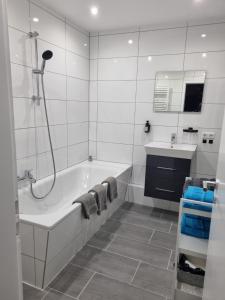 a white bathroom with a tub and a sink at Ferienwohnung Rheinpark Emmerich Rheinblick, Balkon & Parkplatz in Emmerich +34 photos