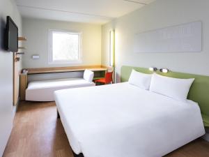 a hotel room with a large white bed and a couch at Ibis Budget Barcelona Sant Andreu De La Barca in Sant Andreu de la Barca +34 photos