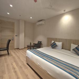 a bedroom with a large white bed and a chair at Bluestone Prime by The Cosy Hotels in New Delhi