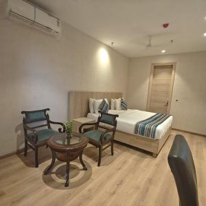a bedroom with a bed and two chairs and a table at Bluestone Prime by The Cosy Hotels in New Delhi