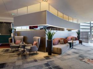 a lobby with a couch and chairs in a building at Novotel Aachen City in Aachen