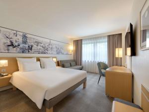 a hotel room with a large white bed and a chair at Novotel Aachen City in Aachen +96 photos