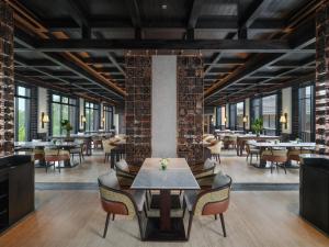 ein Restaurant mit Tischen, Stühlen und Ziegelwänden in der Unterkunft Novotel Bali Ubud Resort in Payangan