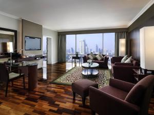 a living room with couches and a large window at Pullman Bangkok Hotel G in Bangkok