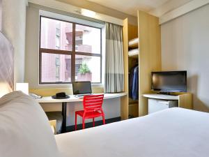 a hotel room with a bed and a desk and a red chair at Ibis Maringa in Maringá