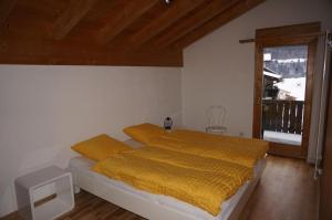 a bedroom with a bed with yellow sheets and a window at Casa Sagogn Laax in Sagogn