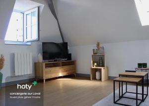 ein Wohnzimmer mit einem Flachbild-TV auf einem Holzschrank in der Unterkunft Apartee - Charmant T2 en centre ville de Laval in Laval