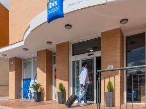 a man with luggage walking out of a store at Ibis Budget Madrid Calle Alcalá in Madrid
