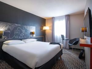 Una habitación de hotel con una cama grande y un escritorio. en Ibis Styles Cognac, en Châteaubernard