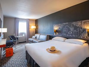 a hotel room with a large bed with a hat on it at Ibis Styles Cognac in Châteaubernard +114 photos