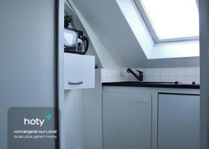 a kitchen with a sink and a skylight at L'escale - charmant studio à Laval in Laval
