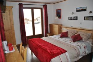 une chambre avec un grand lit avec une couverture rouge dans l'établissement Chalet La Belle Etoile, à La Toussuire