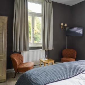 a bedroom with a bed and two chairs and a window at Villa Burgau in Monschau