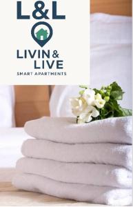 a stack of towels on a bed with a flower at L&L Livin & Live in Arzúa