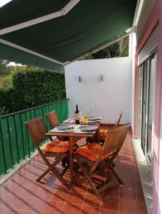 a table and chairs on a patio with a green awning at Granny's House by Trip2Portugal in Carvoeira