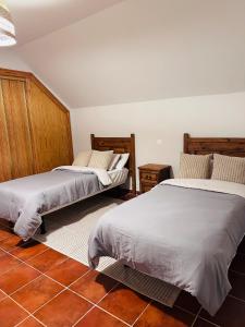 a bedroom with two beds and a tile floor at Casa rústica en paraje natural in El Espinar