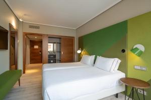 a bedroom with a white bed and a green wall at Eurostars Indautxu in Bilbao +49 photos