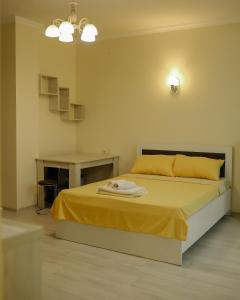- une chambre avec un lit avec des draps jaunes et une table dans l'établissement Batumi city apartments, à Batoumi