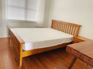 a wooden bed in a room with a window at Living Oasis Home in Auckland
