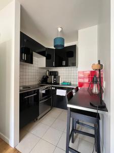 eine Küche mit schwarzen Schränken und einem Tisch darin in der Unterkunft Appartement proche centre d'affaires calme et terrasse in Issy-les-Moulineaux