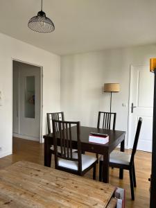 ein Esszimmer mit einem Holztisch und Stühlen in der Unterkunft Appartement proche centre d'affaires calme et terrasse in Issy-les-Moulineaux