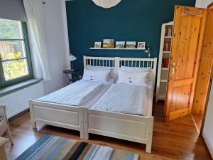 a bedroom with a white bed with a blue wall at FeWo Wichmann in Zehna +2 photos