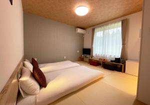 a bedroom with two beds and a large window at Hotel Hanafuji Inn in Furano