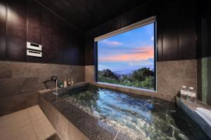 a bathroom with a tub with a large window at Crystal Besso Shirahama in Shirahama +71 photos