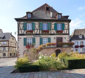 a building with green shutters and flowers on it at Le Cerf in Wintzenheim