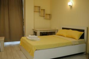 - une chambre avec un lit avec des draps jaunes et une table dans l'établissement Batumi city apartments, à Batoumi
