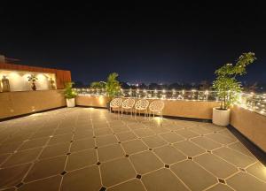 a rooftop patio with chairs and lights at night at Opulence Inn - 500 Meters From Railway Station in Udaipur