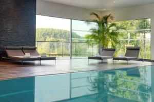 an indoor pool with two chairs and a palm tree in a house at Best Western Plus Le Fairway Hotel & Spa Golf d'Arras in Anzin-Saint-Aubin
