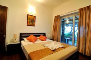 ein Schlafzimmer mit einem Bett mit orangefarbenen Kissen und einem Fenster in der Unterkunft Clouds Holiday Bungalow in Haputale