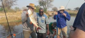 un groupe d'hommes debout sur un bateau tenant un poisson dans l'établissement Marrow camping site, à Sikwanyi