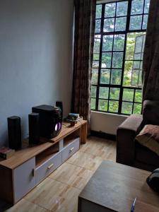 a living room with a tv on a stand with a large window at Banana Grove Retreat in Moshi