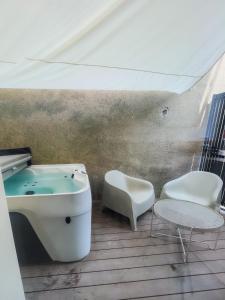 a bathroom with a tub and a table and a chair at Wake up in white - Private Jacuzzi & cotton comfort in Verdun