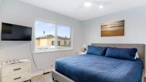 a bedroom with a blue bed and a window at Shelly by AvantStay Steps to the Beach Deck w Ocean Views 5BDR in Newport Beach