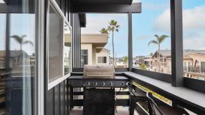 a balcony with a grill and a view of a city at Shelly by AvantStay Steps to the Beach Deck w Ocean Views 5BDR in Newport Beach