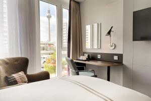a hotel room with a bed and a desk and a window at Premier Inn Berlin Alexanderplatz in Berlin +26 photos