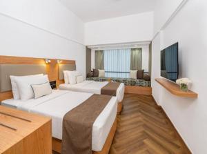 a hotel room with two beds and a couch at Hotel The Grand Olive Aero Suites Near Delhi Airport in New Delhi