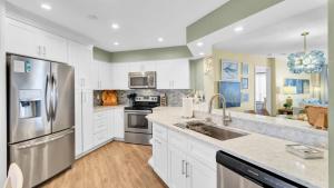a kitchen with white cabinets and stainless steel appliances at 402 Summerhouse by AvantStay Beachfront Condo w Community Pool Access in Isle of Palms