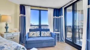 a bedroom with a blue chair and a balcony at 402 Summerhouse by AvantStay Beachfront Condo w Community Pool Access in Isle of Palms